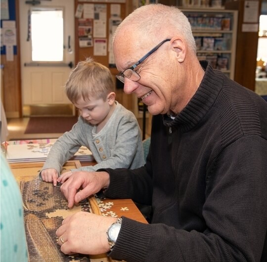 Adult Man Working On Jigsaw Puzzle Together With Child Inside Collinsville Library