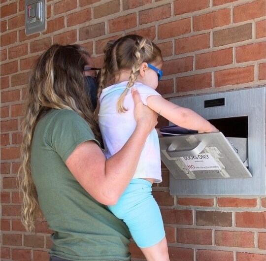 Woman And Young Girl Using Book Drop At Mason Dixon Library